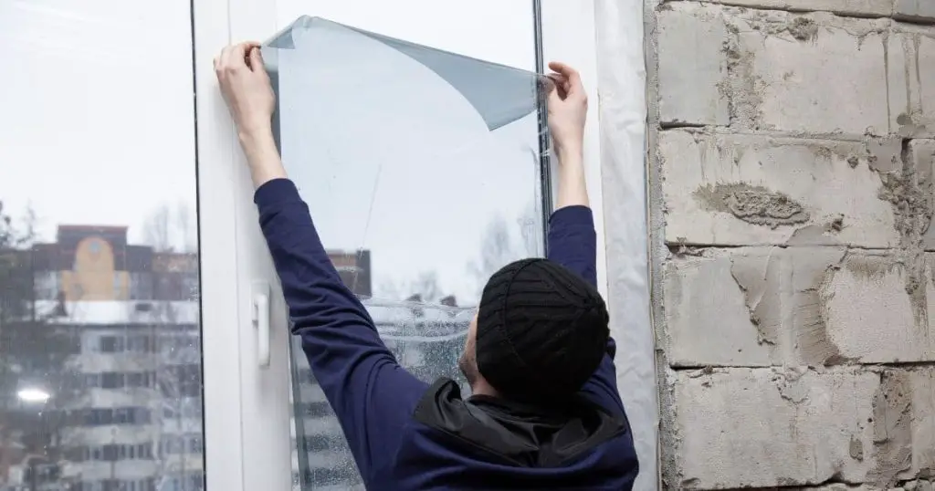 man installing window film